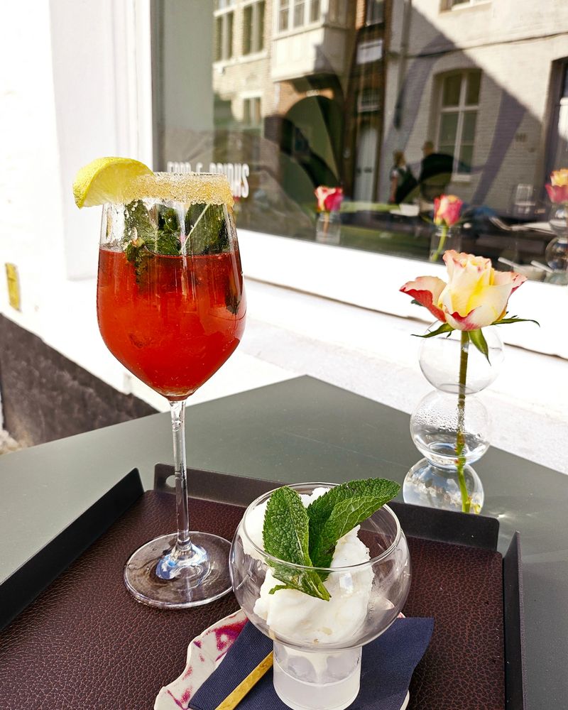 Cocktail met munt en een dessert met een roos op tafel bij het raam
