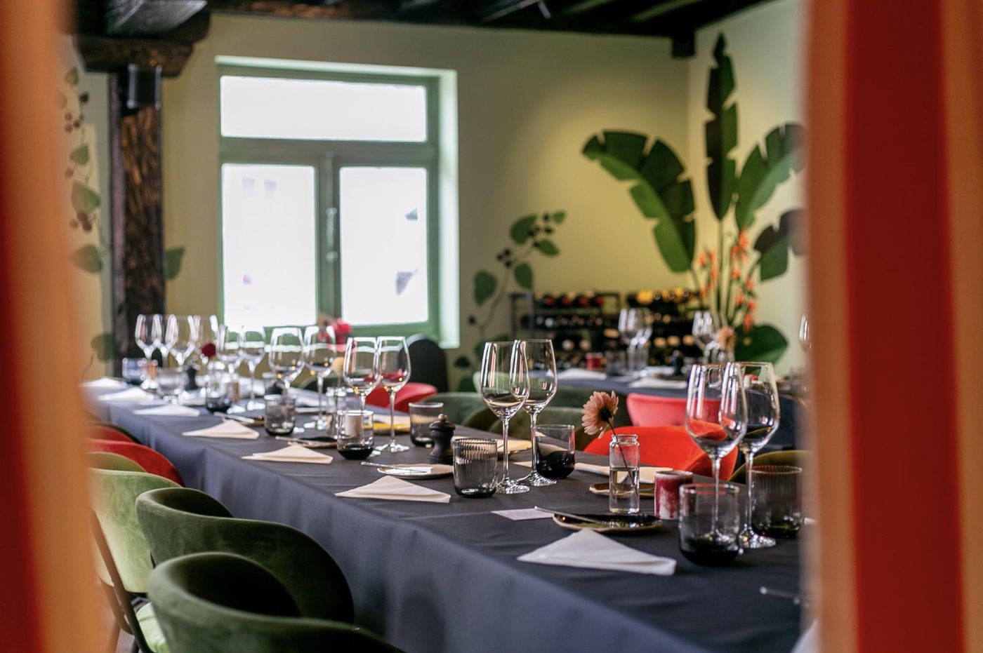 Gedekte feesttafel met groene en rode fluwelen stoelen en een jungleschildering in Bagheera’s